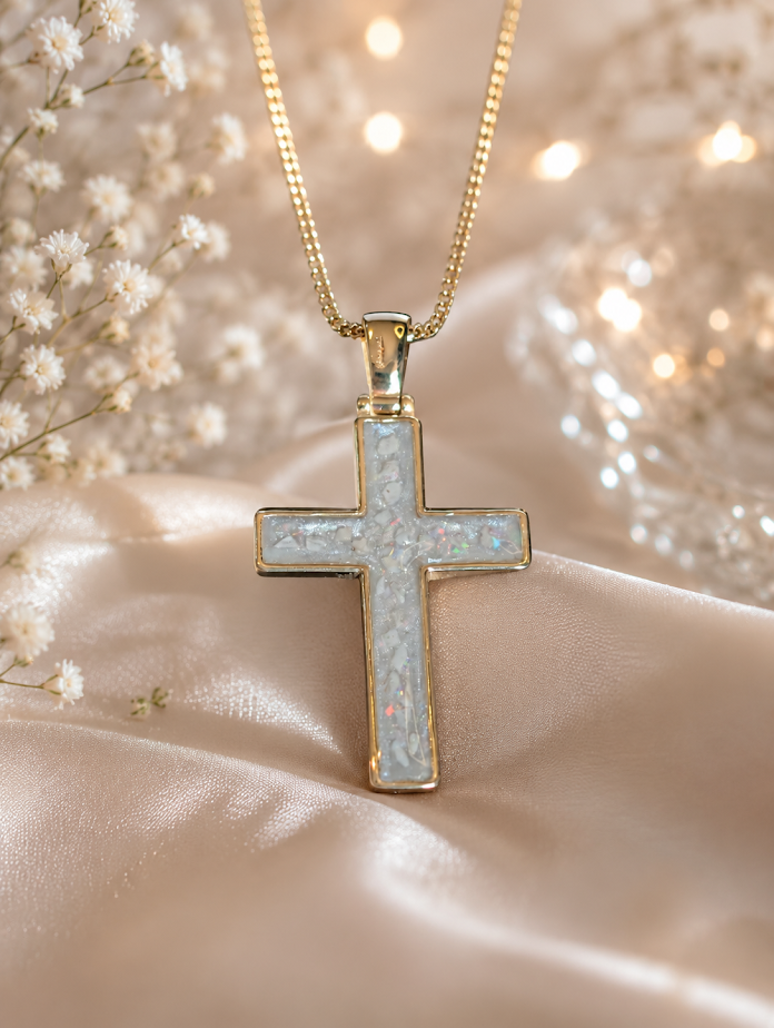 Gold cross pendant with sparkling details on a soft, silky background.
